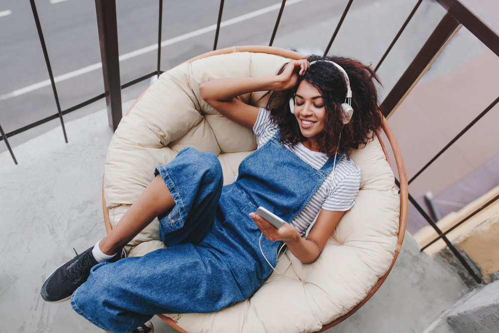 Young woman sitting on her balcony listening to music