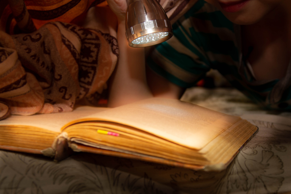 Personne lisant une histoire dans le noir avec une lampe de poche