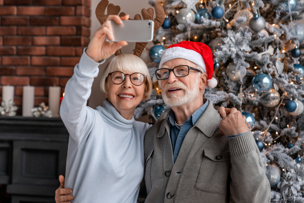 Older couple taking a selfie by their Christmas tree