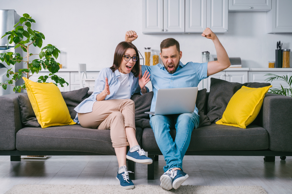 Couple heureux regardant les concours LEO sur leur ordinateur portable