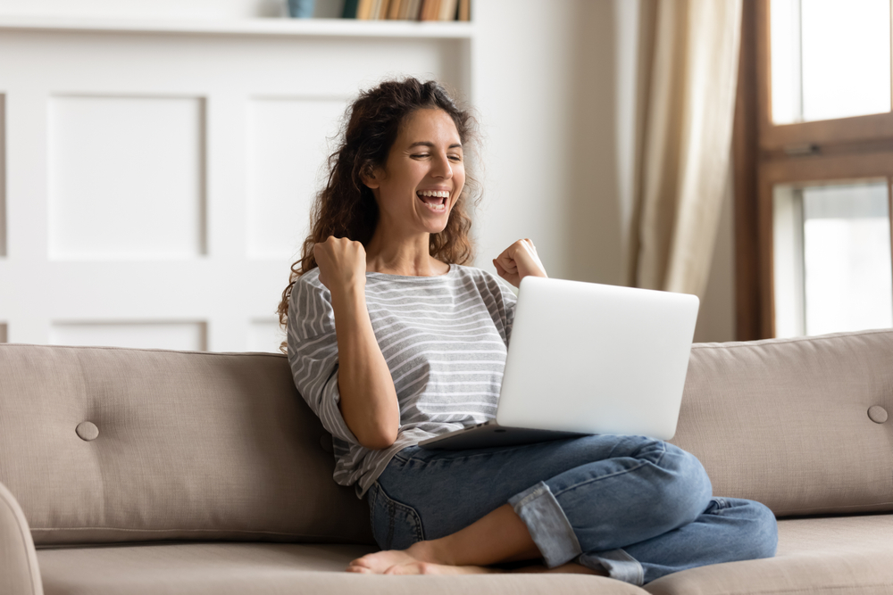 Woman on her laptop celebrating winning a contest
