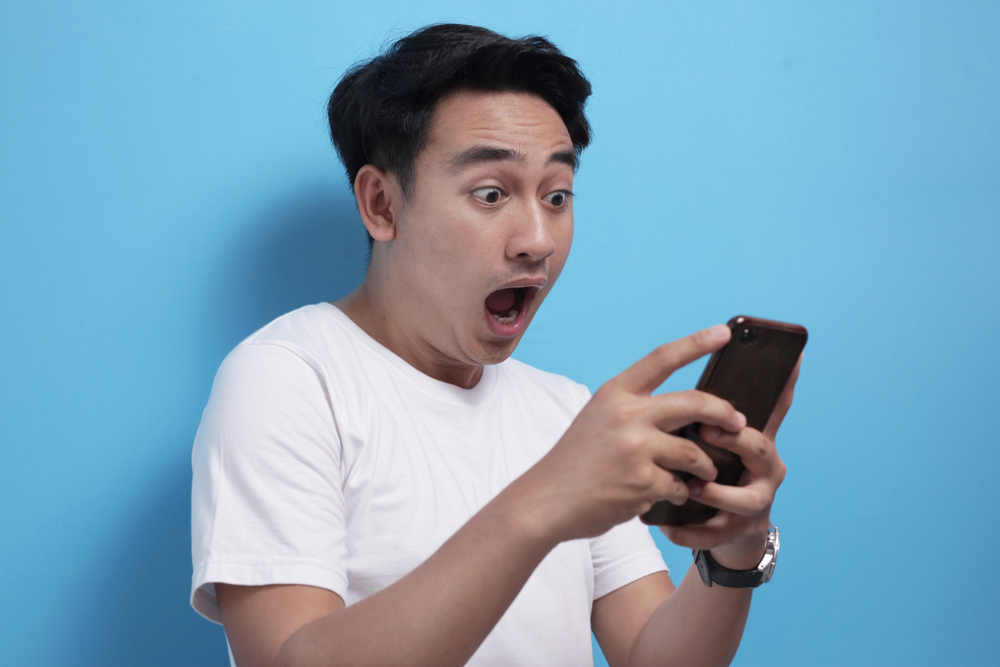 Un homme surpris regardant les concours LEO sur son cellulaire