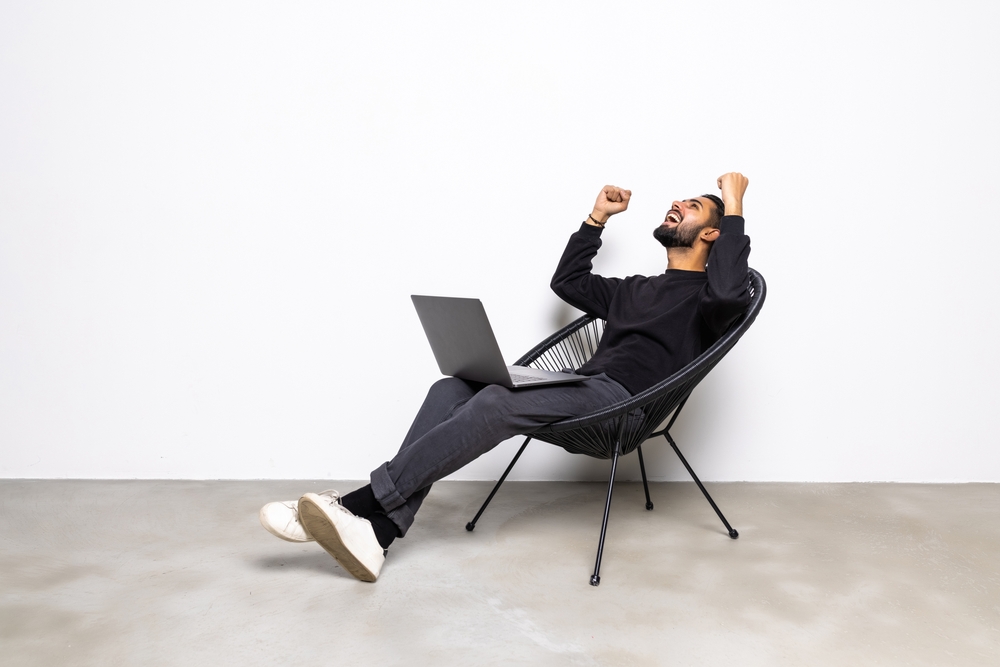 Man with his laptop who is celebrating winning a contest