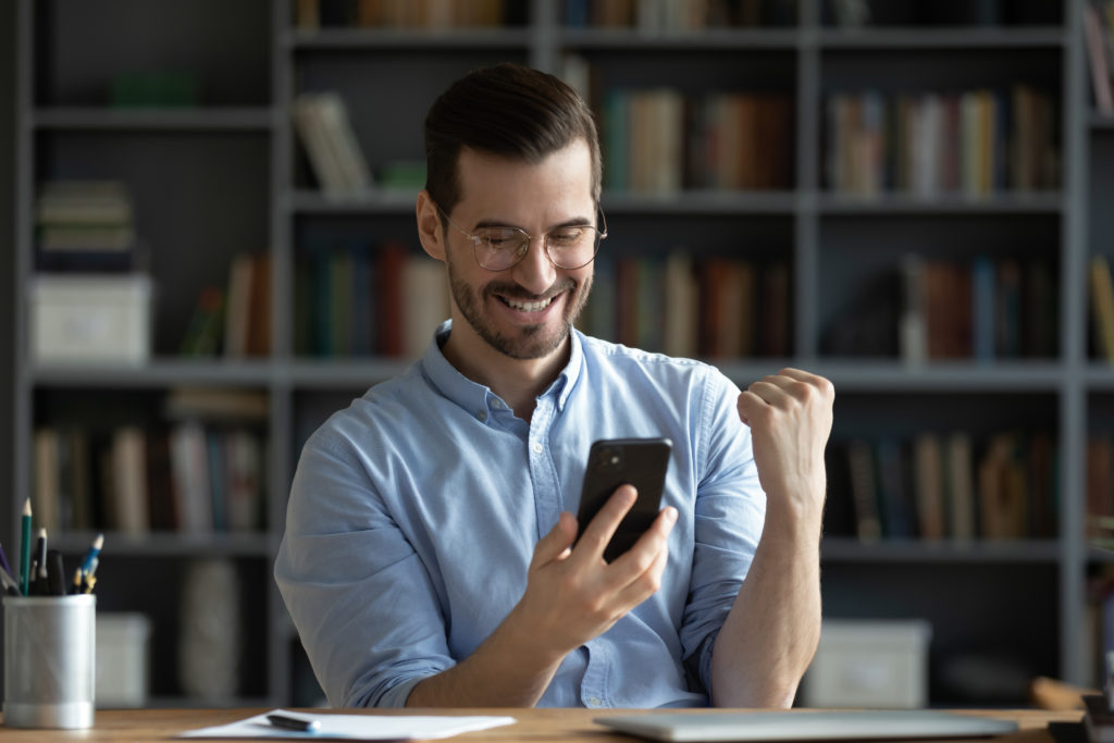 Excited,Smiling,Man,Wearing,Glasses,Holding,Phone,Reading,Good,News
