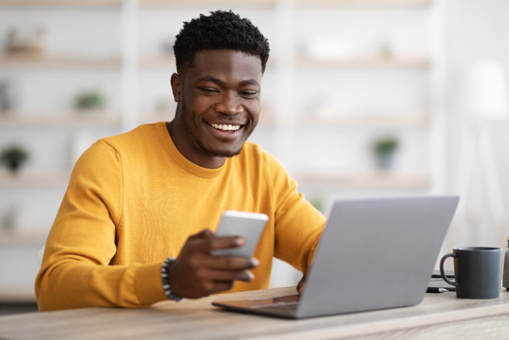 Smiling young man using a smartphone to answer a paid survey on Léger Opinion (LEO) — Canada’s market research platform. Visual representation of mobile engagement in online surveys.