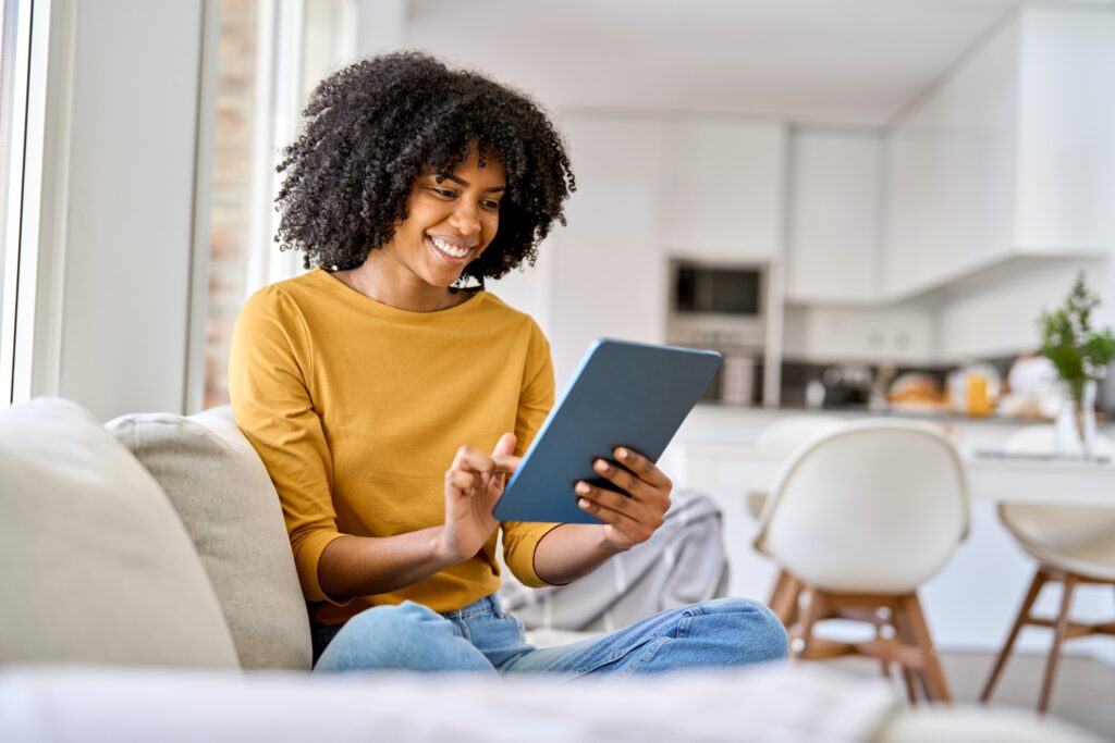Jeune femme souriante utilisant une tablette numérique pour découvrir les concours LEO depuis son salon