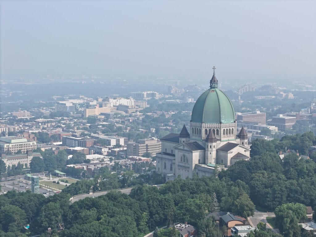 Vue aérienne de l’Oratoire Saint-Joseph à Montréal par une journée d’été brumeuse avec une mauvaise qualité de l’air, entouré de bâtiments urbains et de verdure