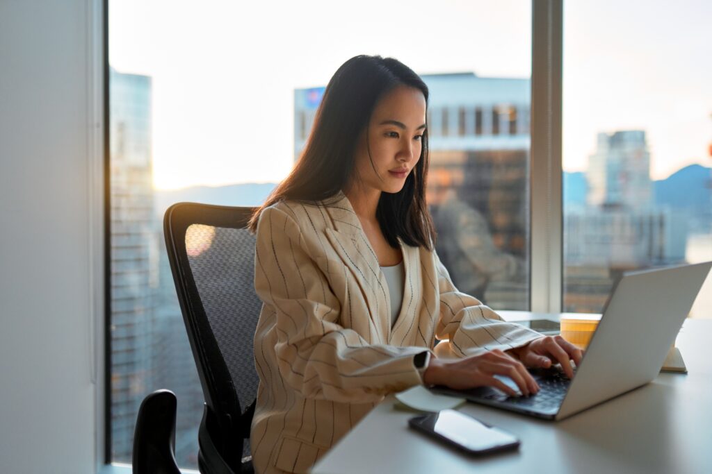 Business professional working on a laptop in a modern office with city view, focused on data analysis while interacting with the LEO platform and its specialized research panels.