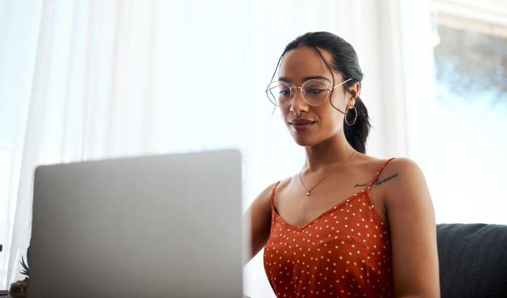 Woman wearing glasses working on a laptop at home while participating in a LEO contest.