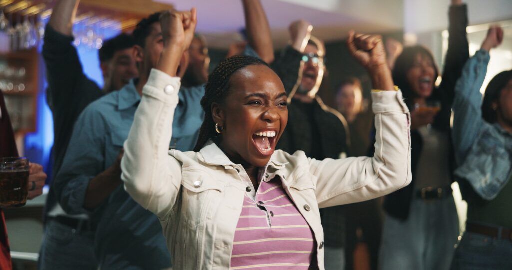 Passionate sports fan celebrating a victory with fellow supporters, capturing the excitement and energy of a live sporting event.