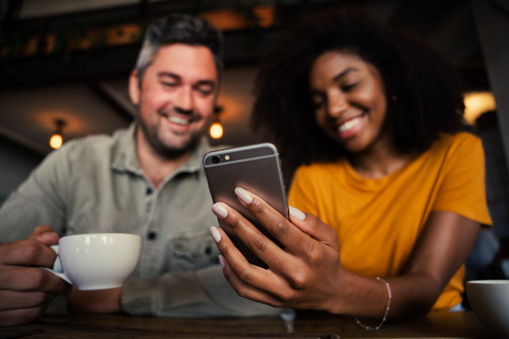Smiling couple using a smartphone together while exploring LEO features and discovering what the platform has to offer.